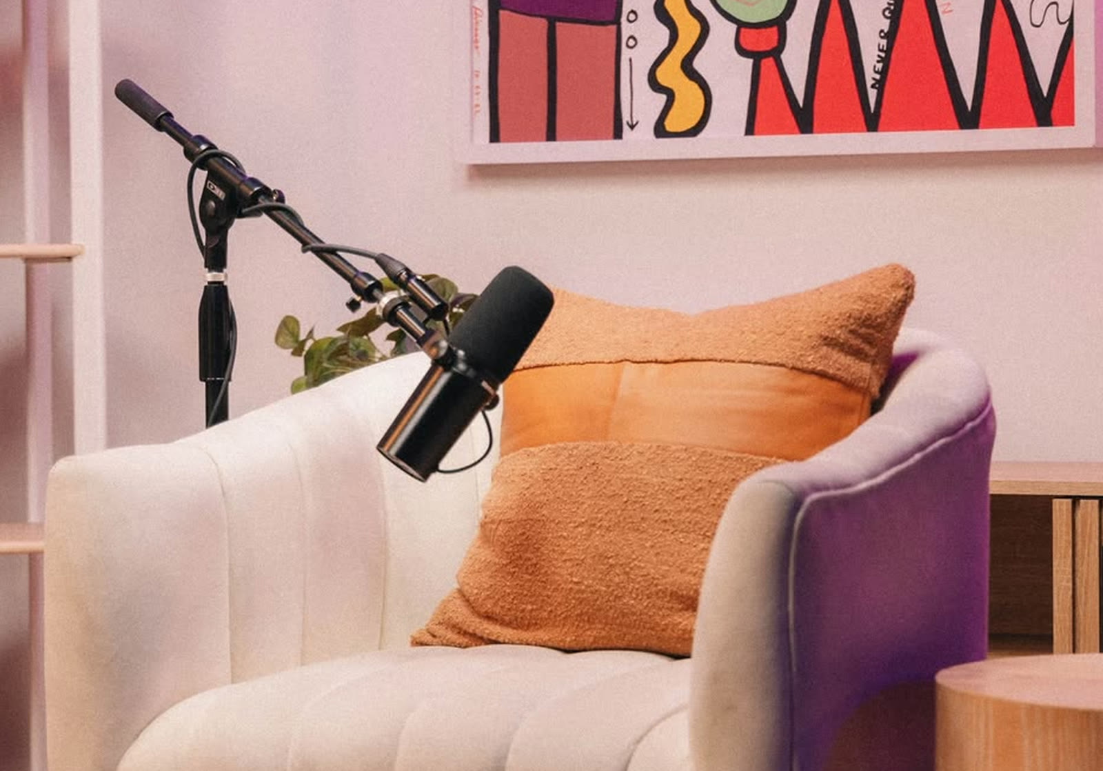 Podcast studio — a boom-arm microphone over a cream and purple armchair with an orange cushion